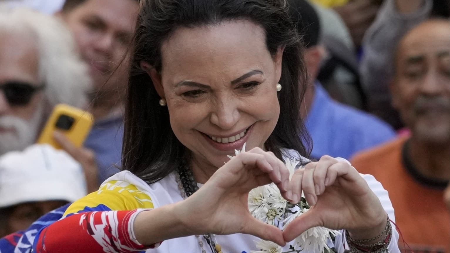 Oppositionsledaren Maria Corina Machado gestikulerar med händerna formade som ett hjärta under en protest mot president Nicolás Maduro i Caracas, Venezuela, omgiven av demonstranter.