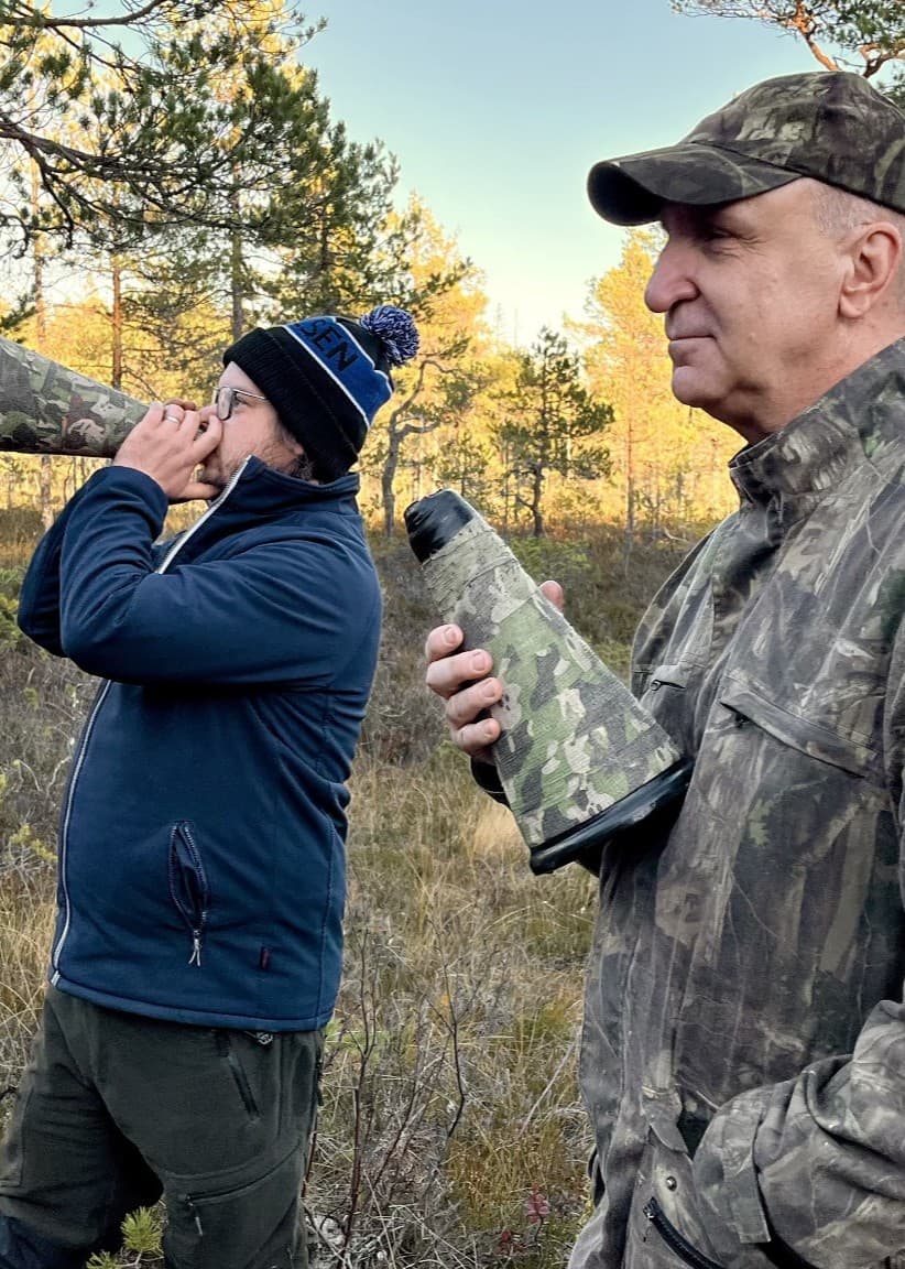 Ove Eriksson från Älgered i Nordanstig och Erik Norberg från Hudiksvall står i en skog med älglock i händerna, omgivna av höstfärger, och försöker locka fram älgar.