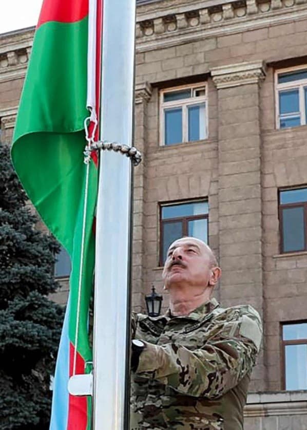 En man i militäruniform hissar en grön och röd flagga.