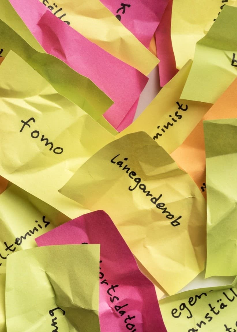 Till vänster syns färgglada post-it-lappar med ord som 'linguistics'. Till höger står en person i svart jacka på en stadsgata med byggnader och blå himmel i bakgrunden.