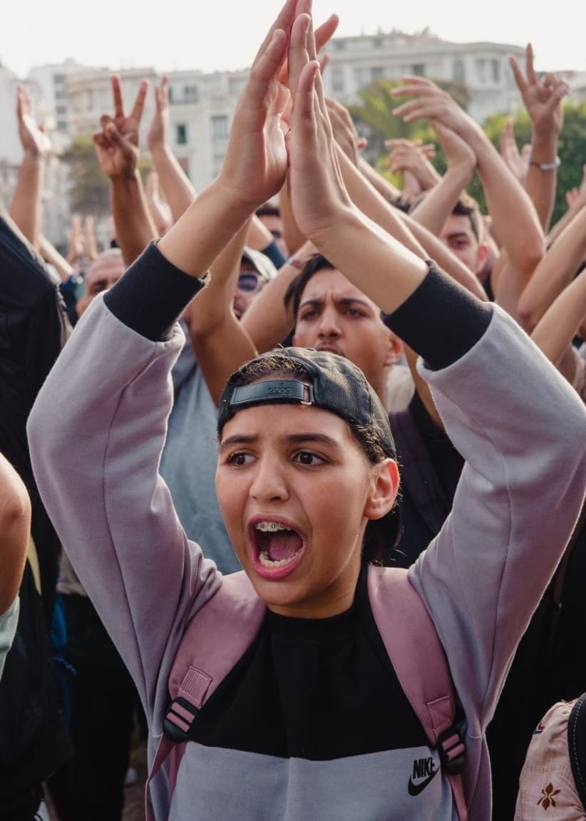 Unga demonstranter med höjda armar. 