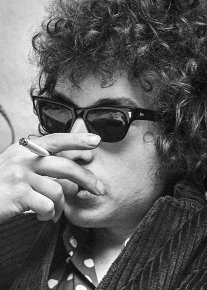 Bob Dylan med solglasögon på sig och en cigarett i handen vid en presskonferens i Solna 28:e april 1966, 