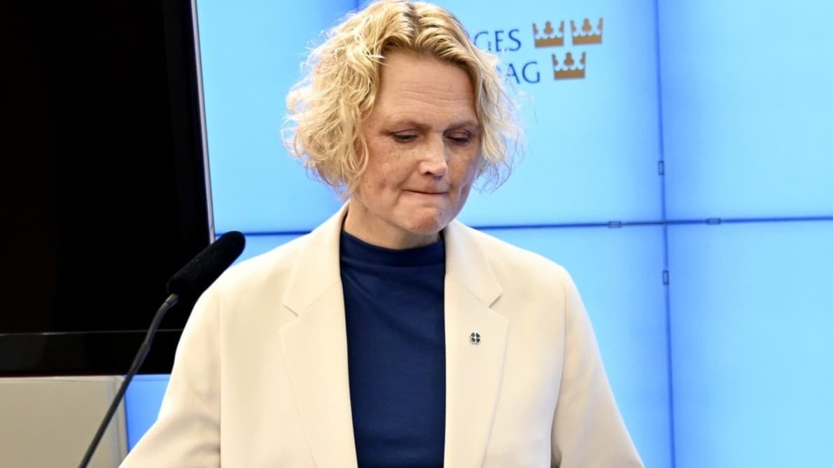 Centerpartiets partiledare Anna-Karin Hatt står vid ett podium under en pressträff i Stockholm. Hon har på sig en vit kavaj och blå topp, med papper och ett glas vatten framför sig.