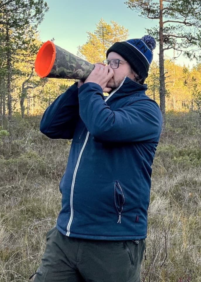 Ove Eriksson från Älgered i Nordanstig och Erik Norberg från Hudiksvall står i en skog med älglock i händerna, omgivna av höstfärger, och försöker locka fram älgar.