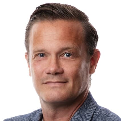 Victor Nilsson Lindelöf i fotbollslandslagets träningskläder sitter vid ett bord med mikrofon under en pressträff i Stockholm. Bakom honom syns en gul vägg med sponsorer och logotyper.