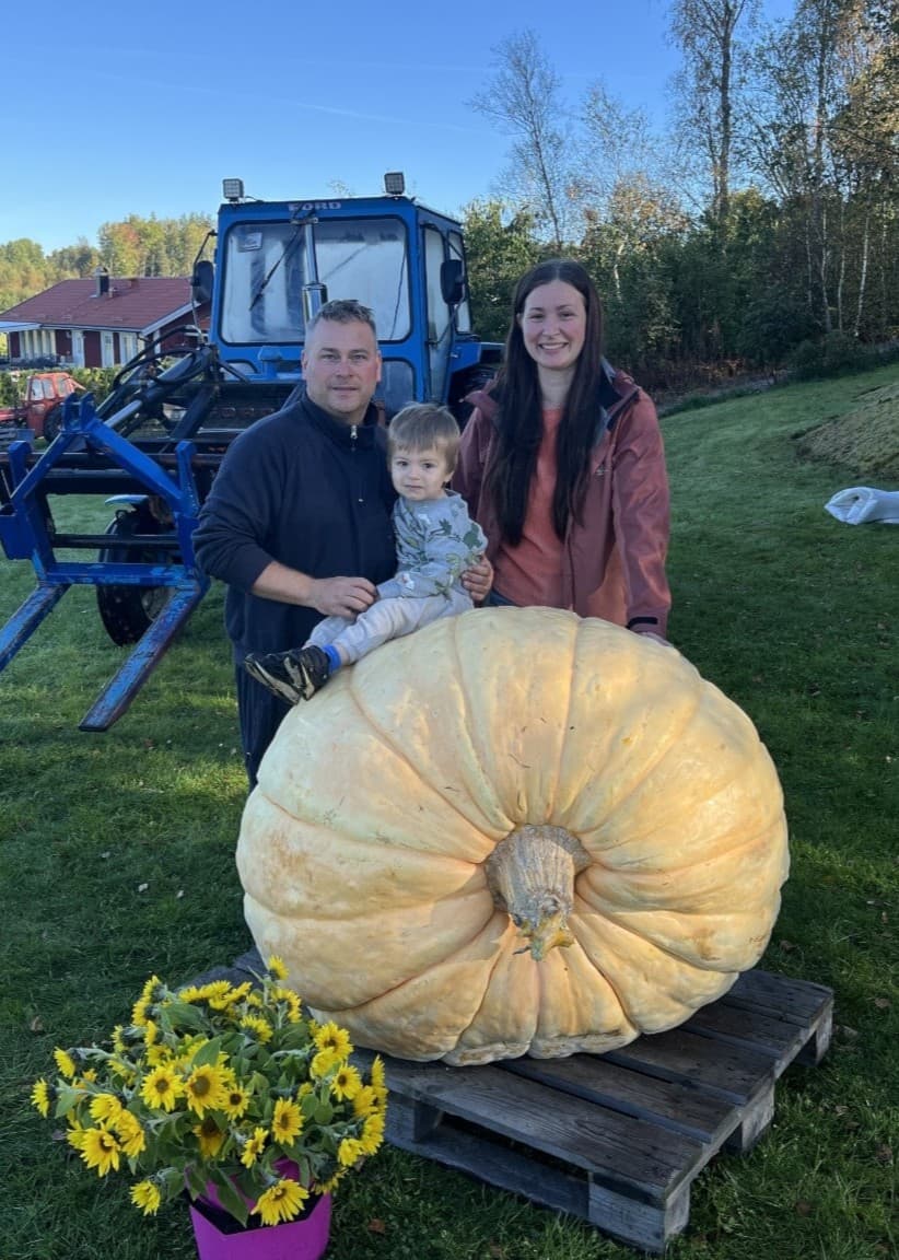 Sofia och Micke från Sorunda poserar med en enorm pumpa. Pumpan är ljusorange och dominerar bilden.