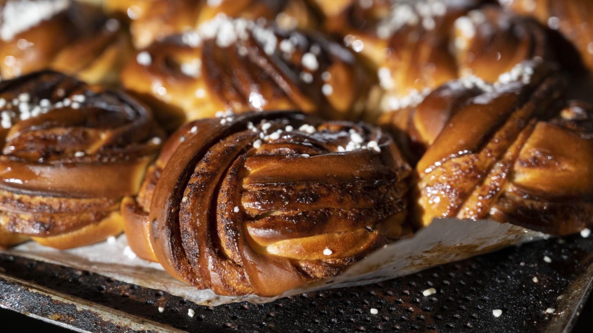 Nygräddade kanelbullar på en plåt, gyllenbruna och toppade med pärlsocker. Priset för att baka kanelbullar hemma har ökat mest de senaste fem åren, enligt ny statistik.