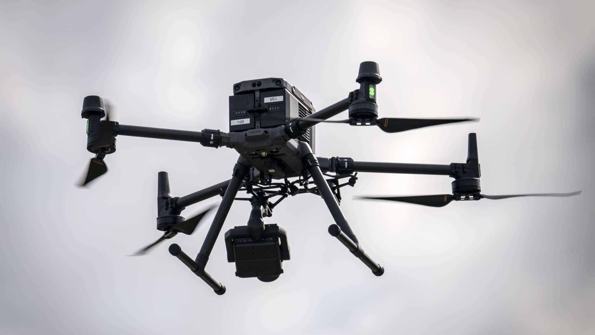 Polisens drönare Matrice 350 RTK av quadcopter-typ flyger i grått molnigt väder. Den används vid insats efter att en misstänkt granat hittats i en damm i Vintrie utanför Malmö.