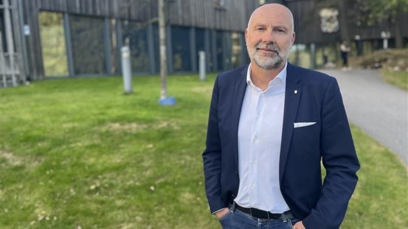 Håkan Mild, avgående klubbdirektör för IFK Göteborg, står utomhus i kostym med händerna i fickorna framför en modern byggnad och grön gräsmatta.