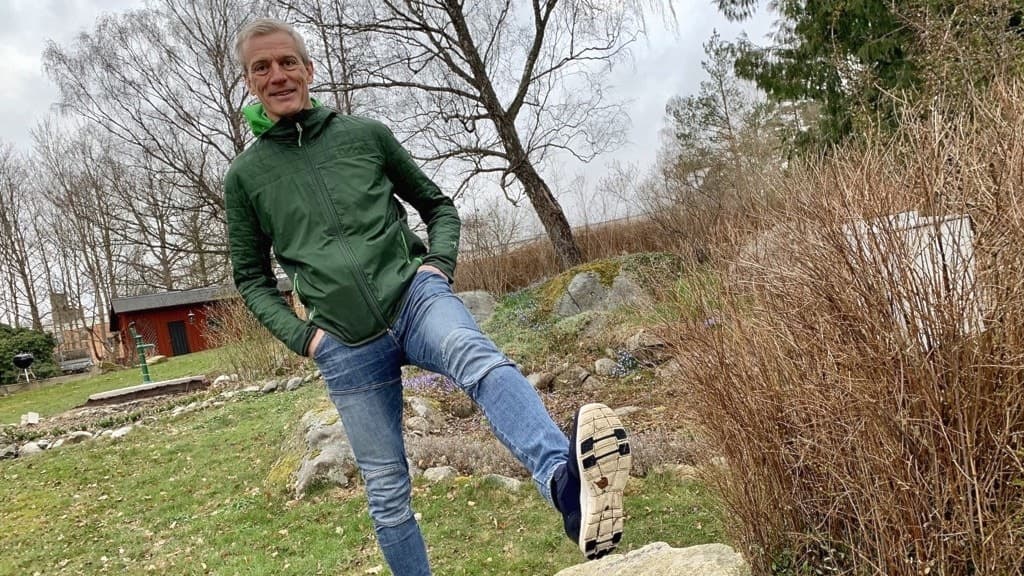 En man står och balanserar på en sten och lyfter upp sitt vänsterben i luften. 
