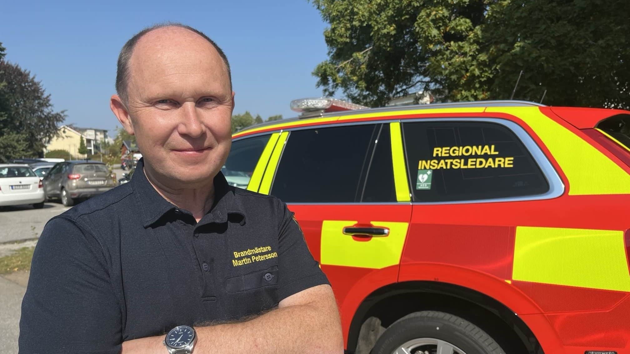 Martin Petersson, regional insatsledare för Räddningstjänsten Kronoberg Öst, står framför en röd insatsbil med gula reflexdetaljer och texten 'Regional insatsledare' på sidan.