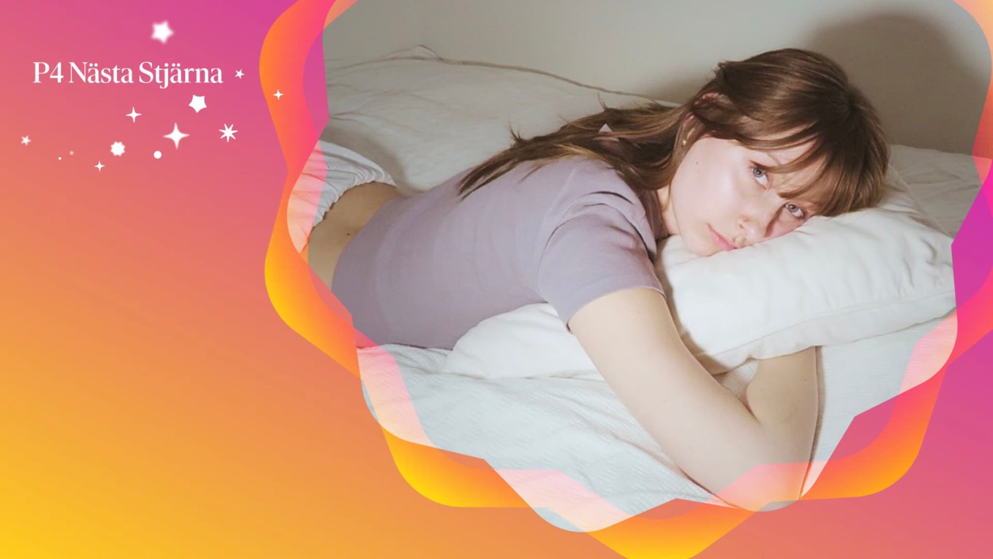 Amanda Lake, finalist i musiktävlingen, ligger avslappnat på en vit kudde med en färgglad bakgrund. Texten 'Nästa Stjärna' visas mot en gradient i rosa och orange.