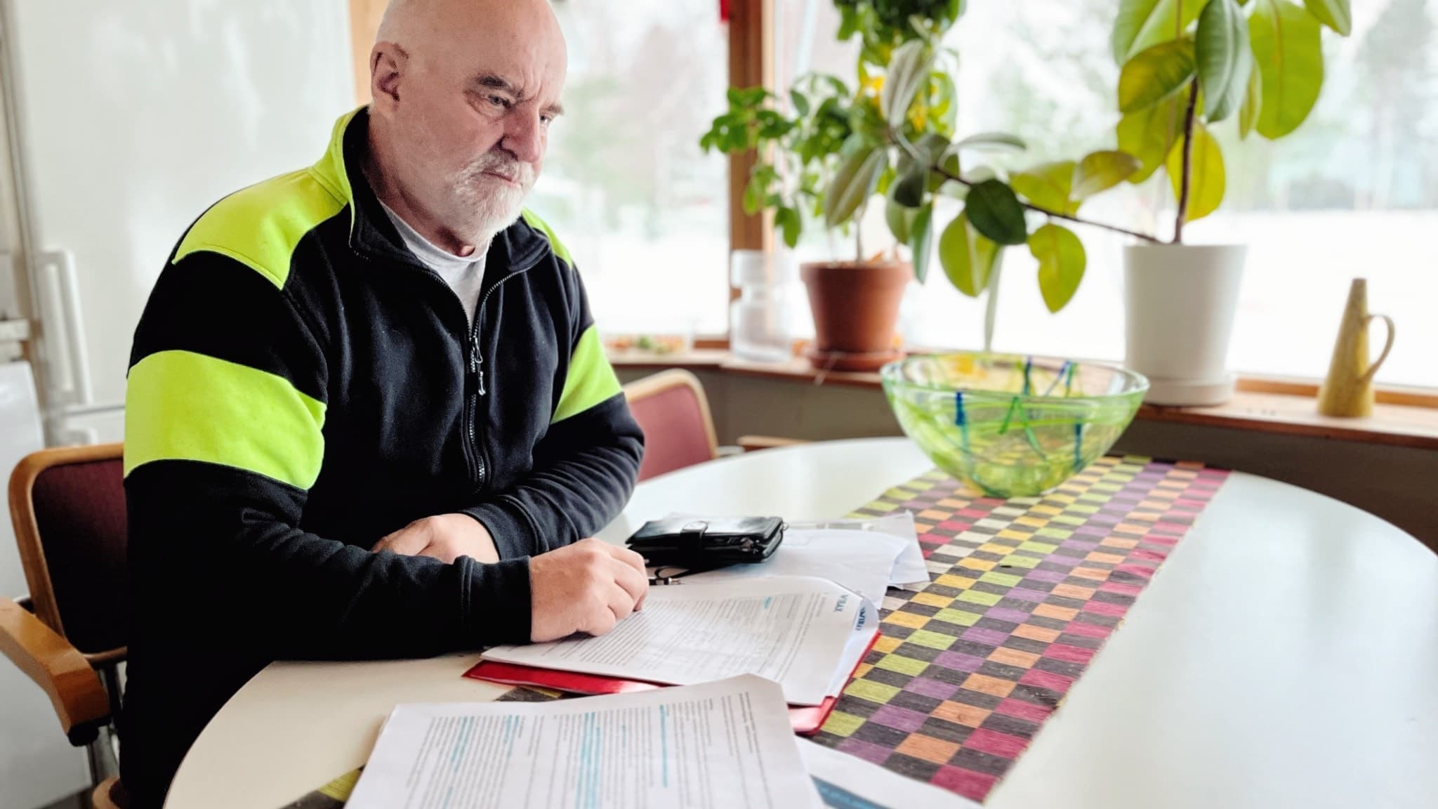 Skelleftehamnbon Martin Eriksson fotograferad vid sitt köksbord där han sitter med handlingar upplagda framför sig.
