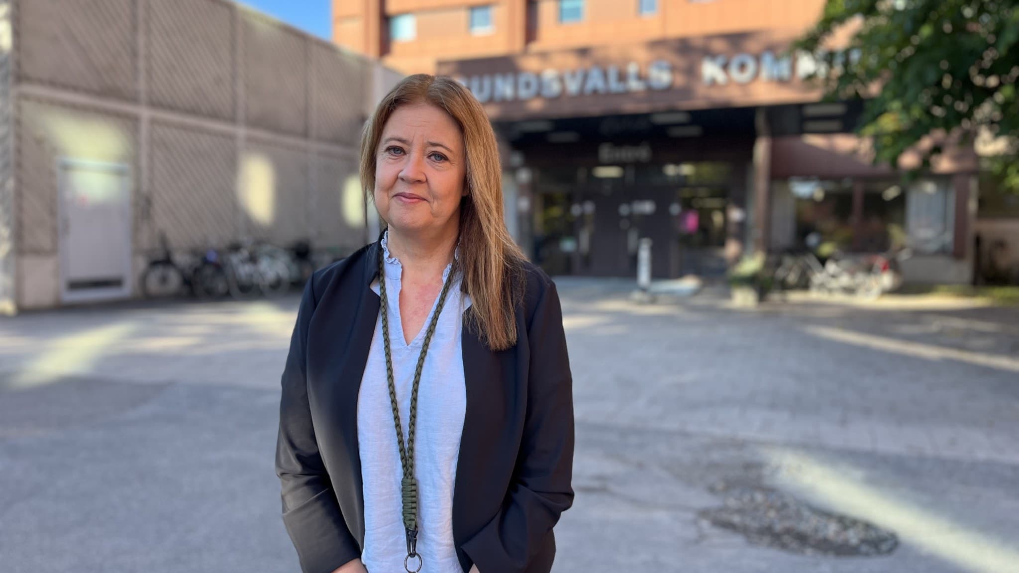 Maria Cederberg, verksamhetschef på servicecenter Sundsvalls kommun, står framför kommunens byggnad i dagsljus. Hon bär en svart kavaj och vit skjorta, med byggnaden synlig i bakgrunden.