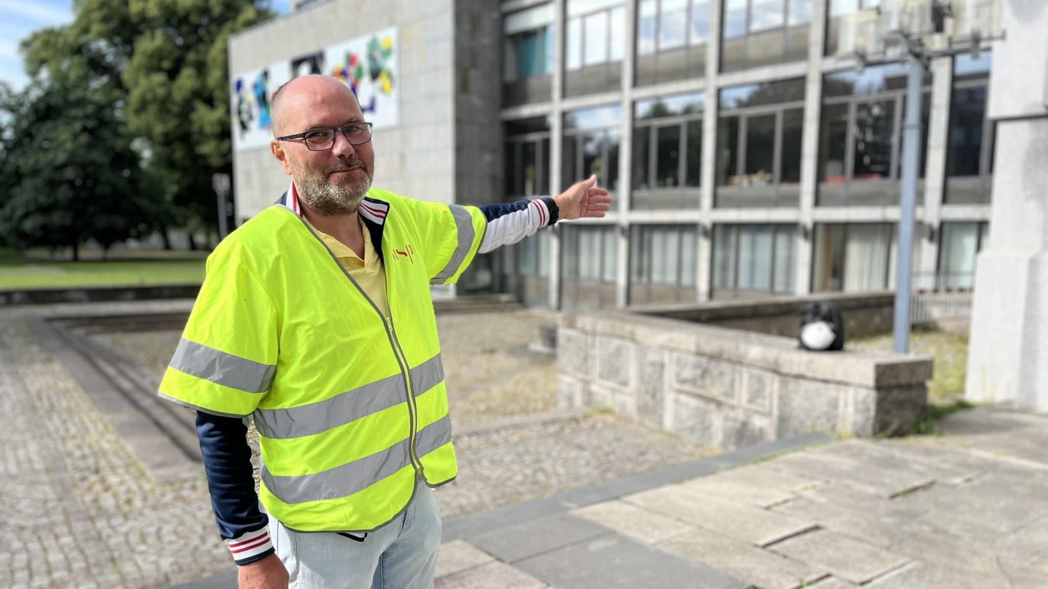 En man står och pekar med en byggnad. Källaren i stadshuset i Västerås ska genomgå en renovering.