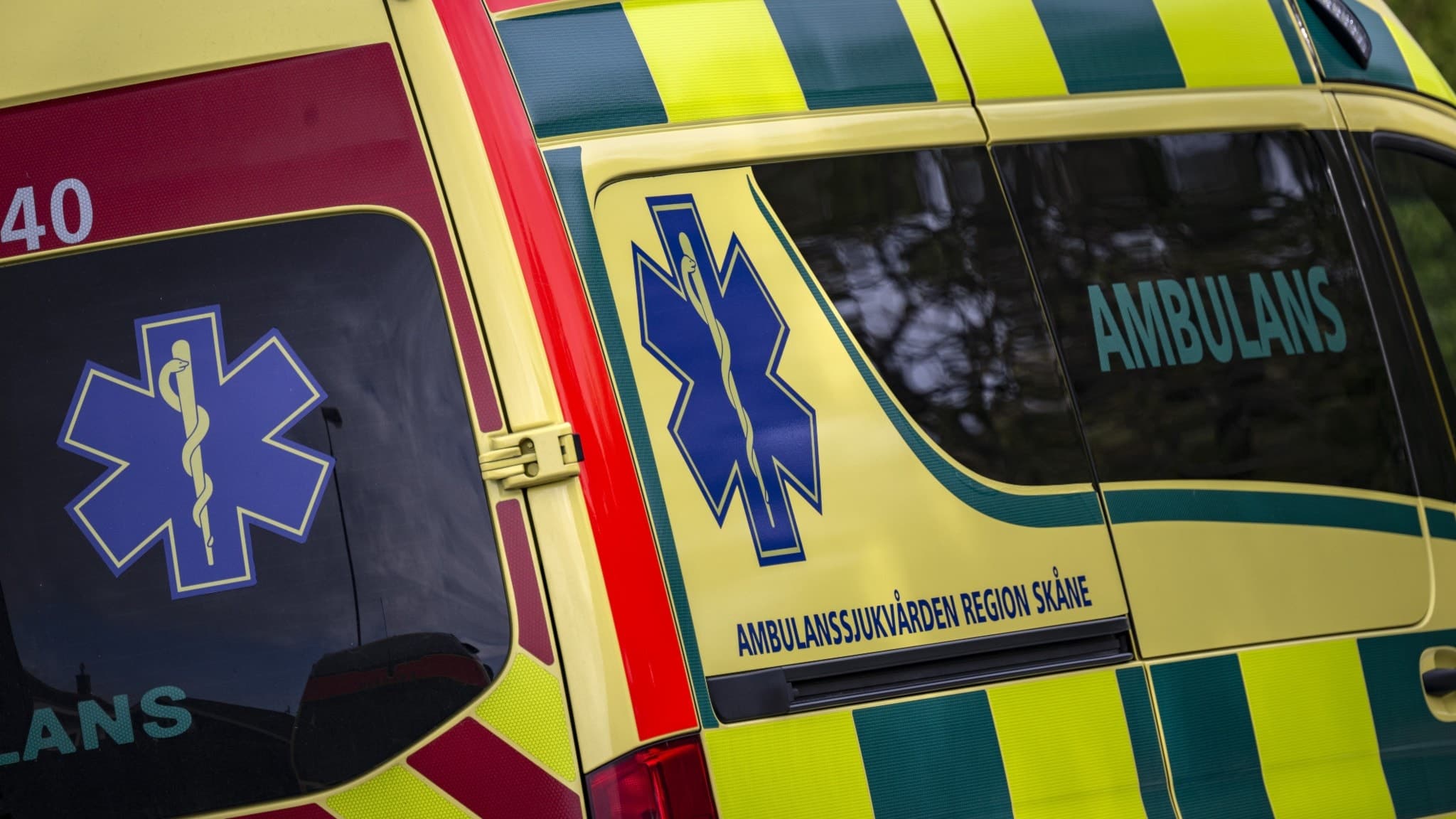 En ambulans. Bilden visar tydligt ambulansens gula och gröna färger samt dess blå medicinska symbol.