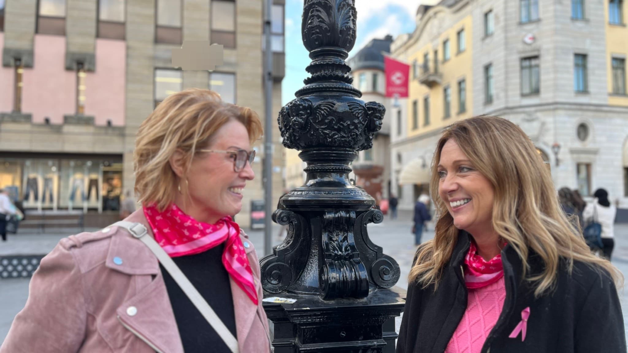 Boel Söderman och Lisa Thörn från Bröstcancerföreningen i Uppsala län står på Stora torget, båda bär rosa detaljer som symbol för kampen mot bröstcancer.