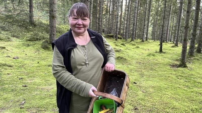 Svampkonsulenten Malin Mobrandt står i en grönskande skog med en korg fylld med svamp och utrustning, redo att identifiera falska svampar och ge råd om svampplockning.