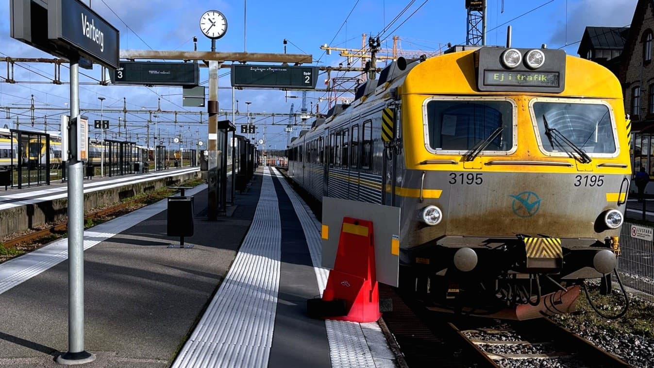 Ett västtåg som står still på Varbergs station och en kö till en busshållplats.