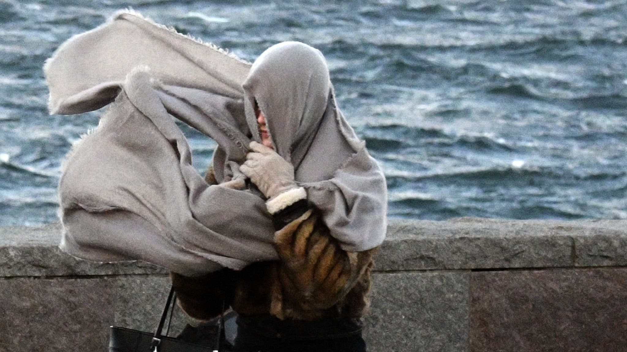 En kvinna kämpar i vinden.