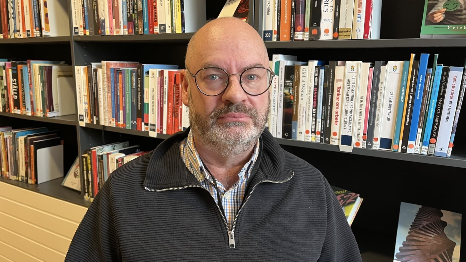 Experten på brottsåterfallsförebyggande arbete, Martin Lardén från Kriminalvården sitter framför en bokhylla fylld med böcker. Han har på sig en mörk tröja och skjorta, i Kriminalvårdens huvudkontors bibliotek i Norrköping.