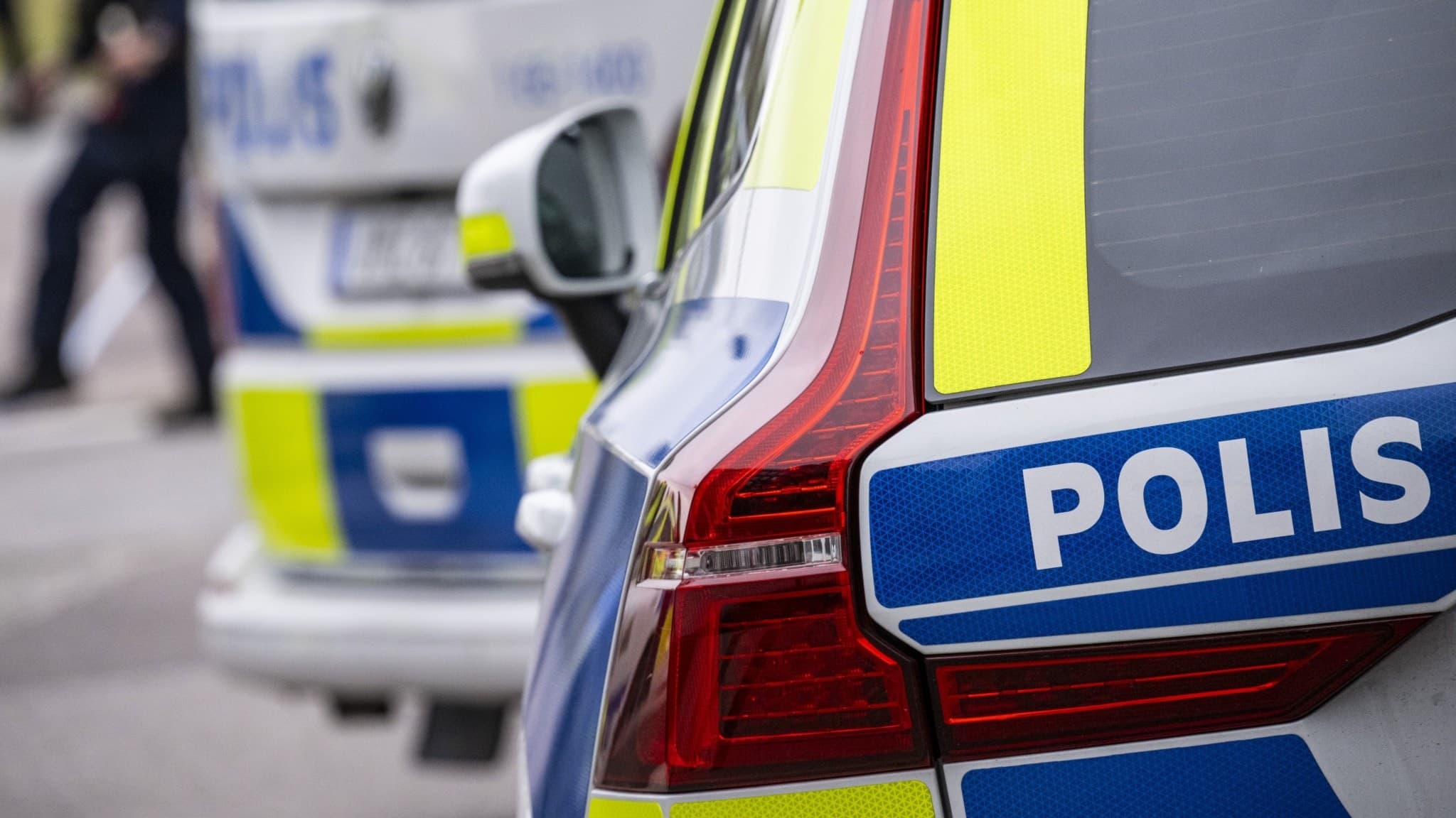 Polisbilar står parkerade. Uniformerad polis syns i bakgrunden. 