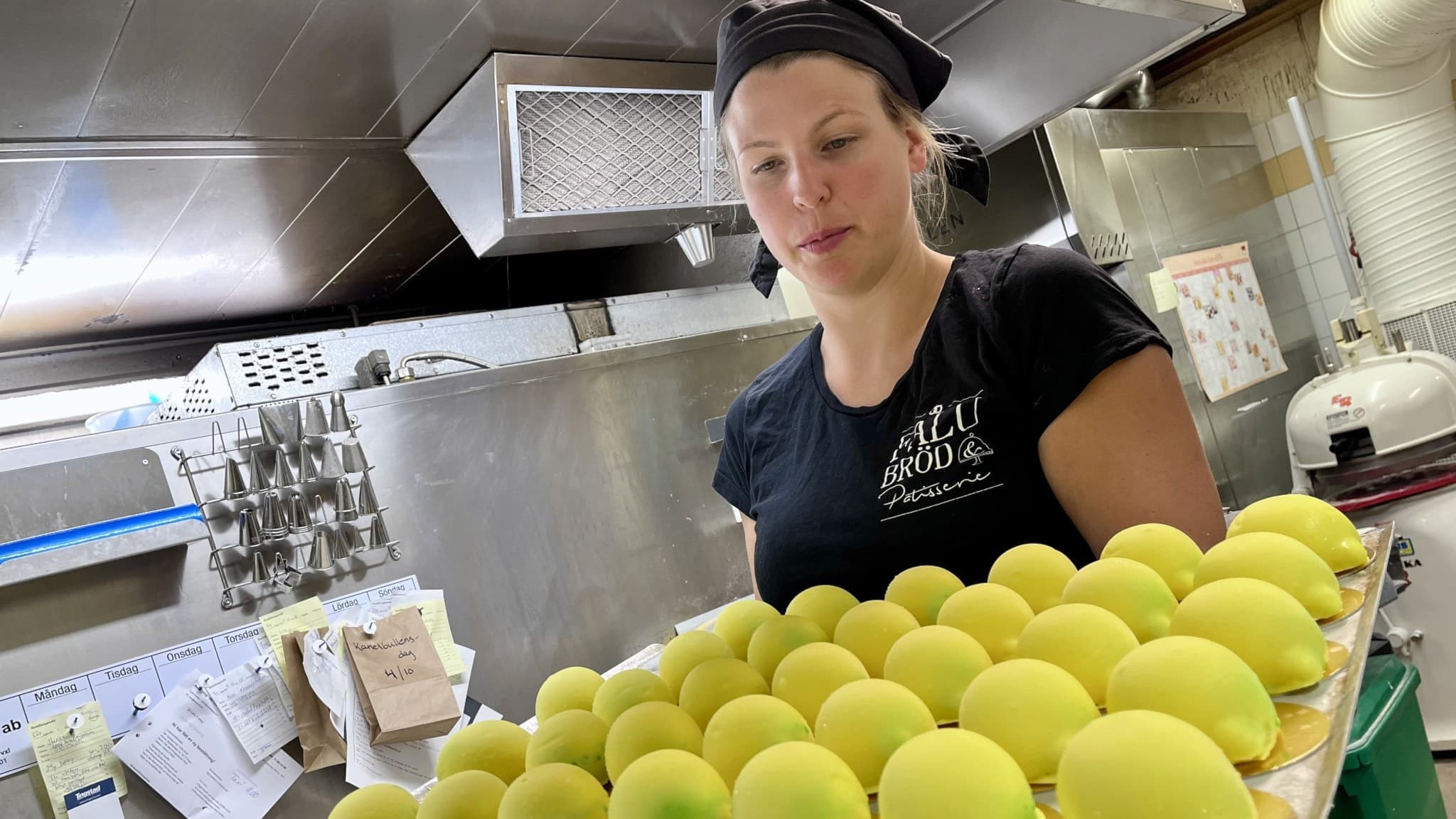 Therese Vesterholm, bageriägare i Falun, håller en bricka med flera gula citronformade fruktbakelser i ett bageri. 
