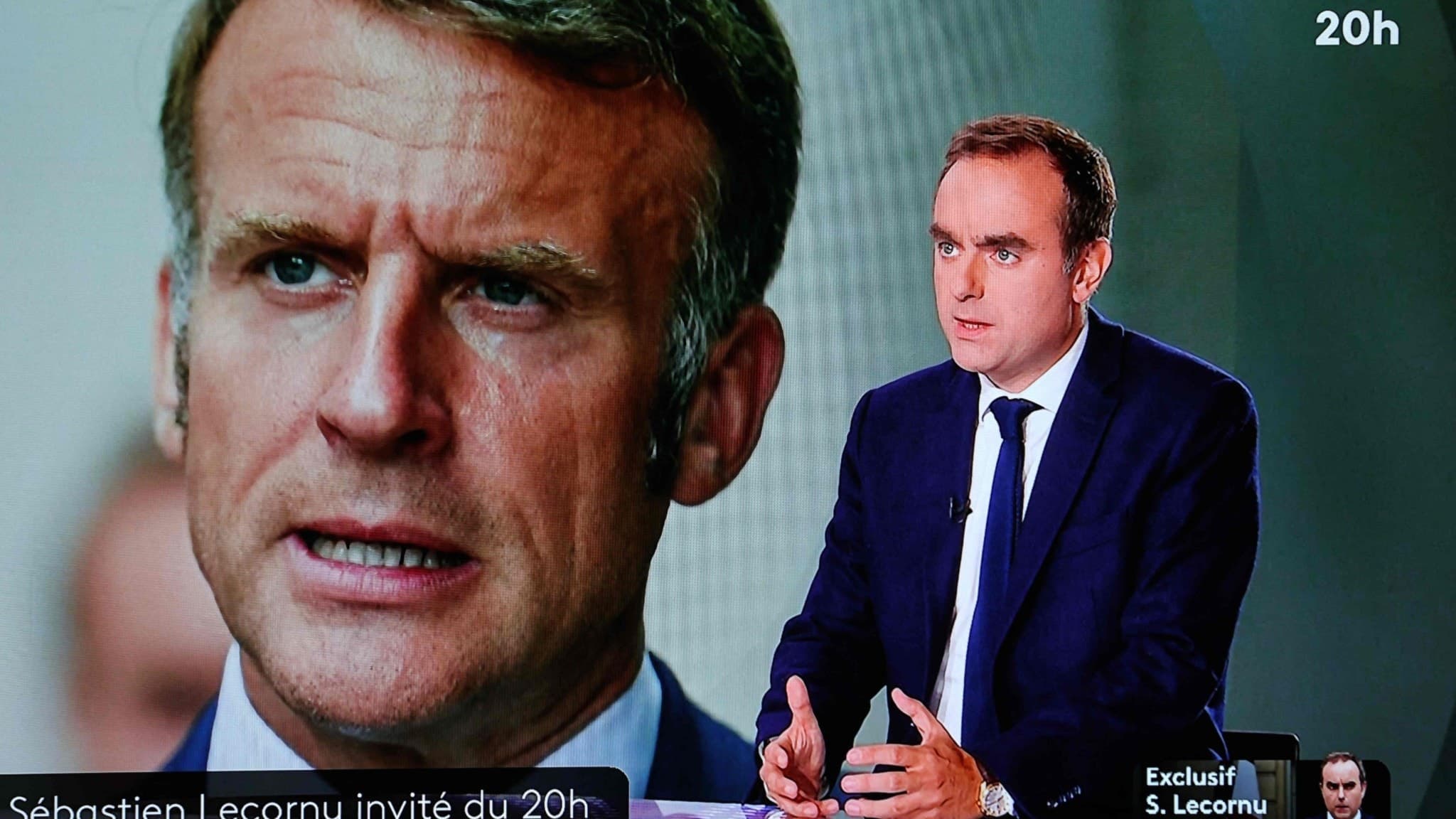 En TV-skärm visar Frankrikes avgående premiärminister Sébastien Lecornu under en intervju på France 2, med en bild av president Emmanuel Macron i bakgrunden. Text på skärmen indikerar programmet.