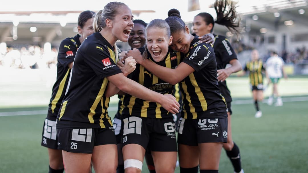 Häckens fotbollsspelare firar mål på Bravida Arena under matchen i damallsvenskan mot Hammarby. Anna Anvegård står i centrum efter att ha gjort 2-0, omgiven av glada lagkamrater i gulsvarta dräkter.