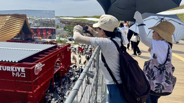 Besökare fotograferar i hettan på världsutställningen i Osaka. 