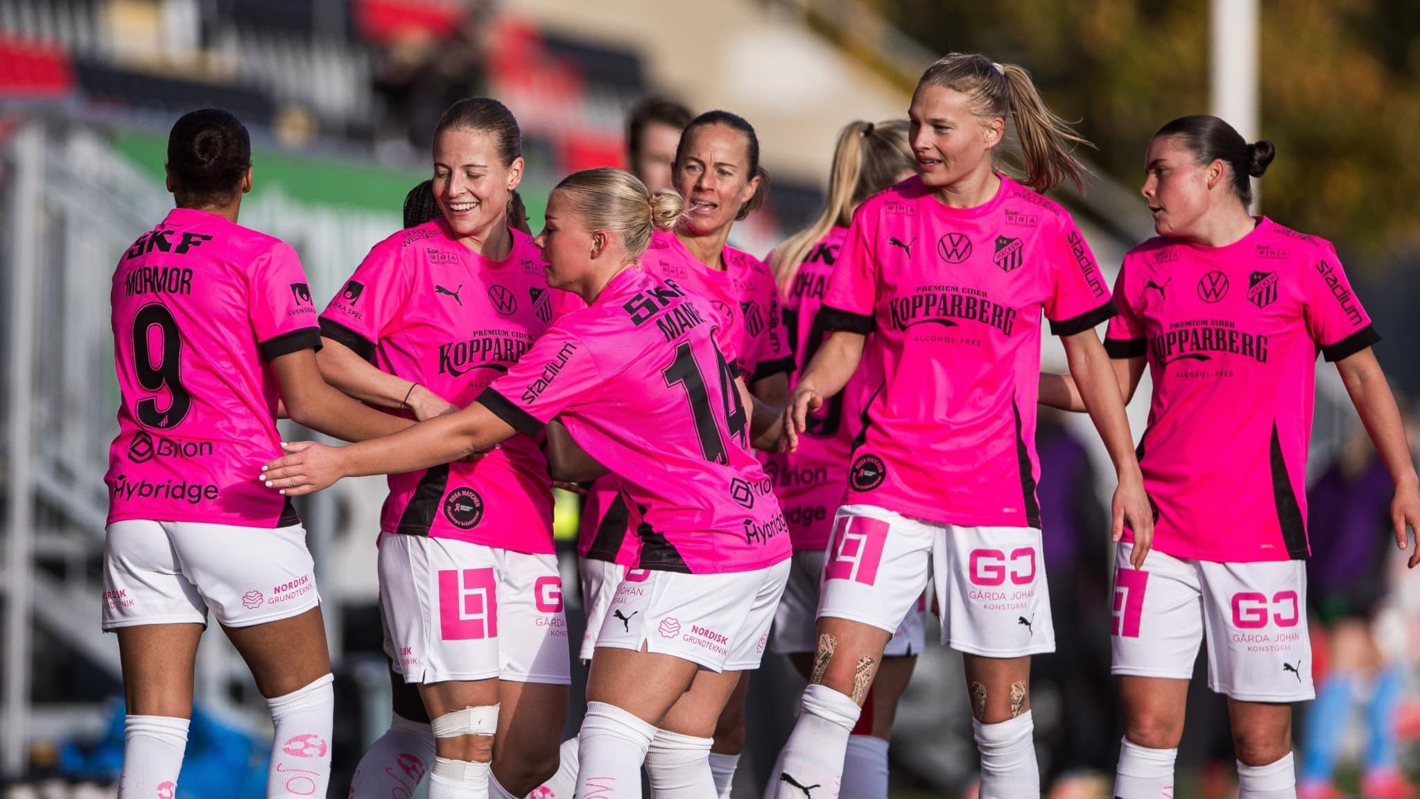 Fotbollsspelare i rosa tröjor kramas i en ring