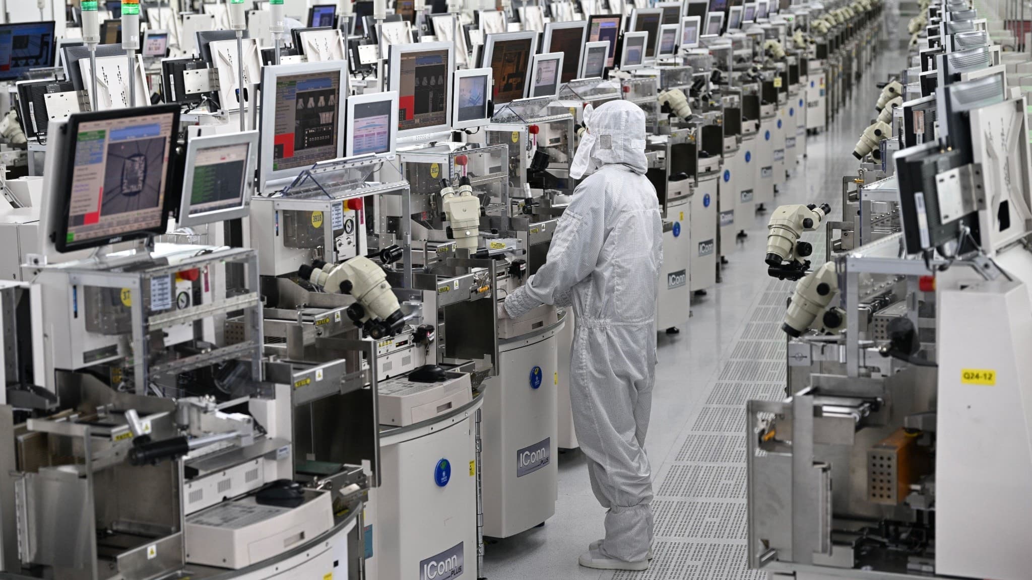 En tekniker i skyddsdräkt arbetar vid chipbearbetningsutrustning på en halvledarfabrik i Kina.