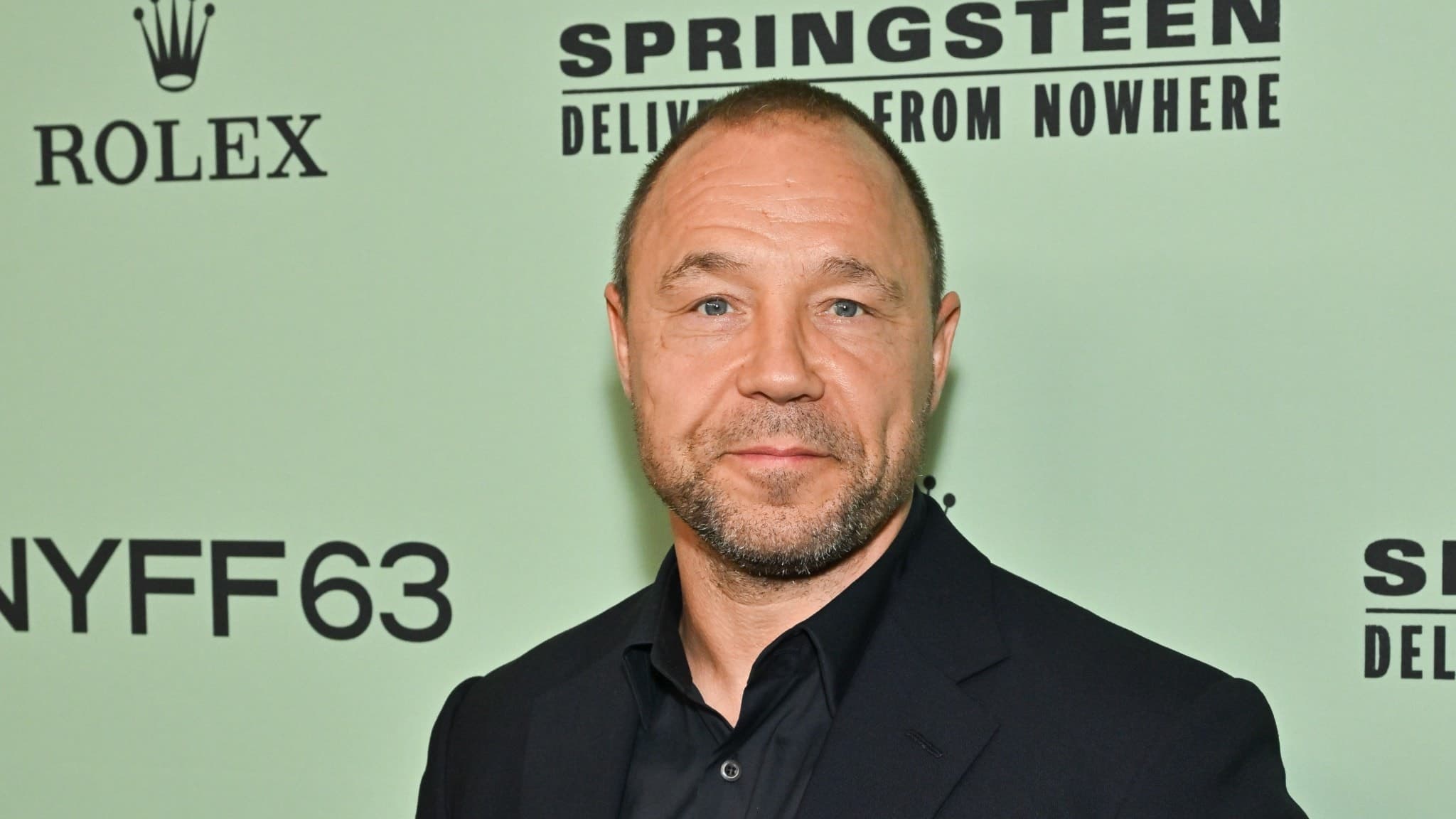 Stephen Graham står framför en mintgrön bakgrund med texten 'Springsteen: Deliver Me From Nowhere' och 'NYFF63' vid premiären av filmen under New Yorks filmfestival.