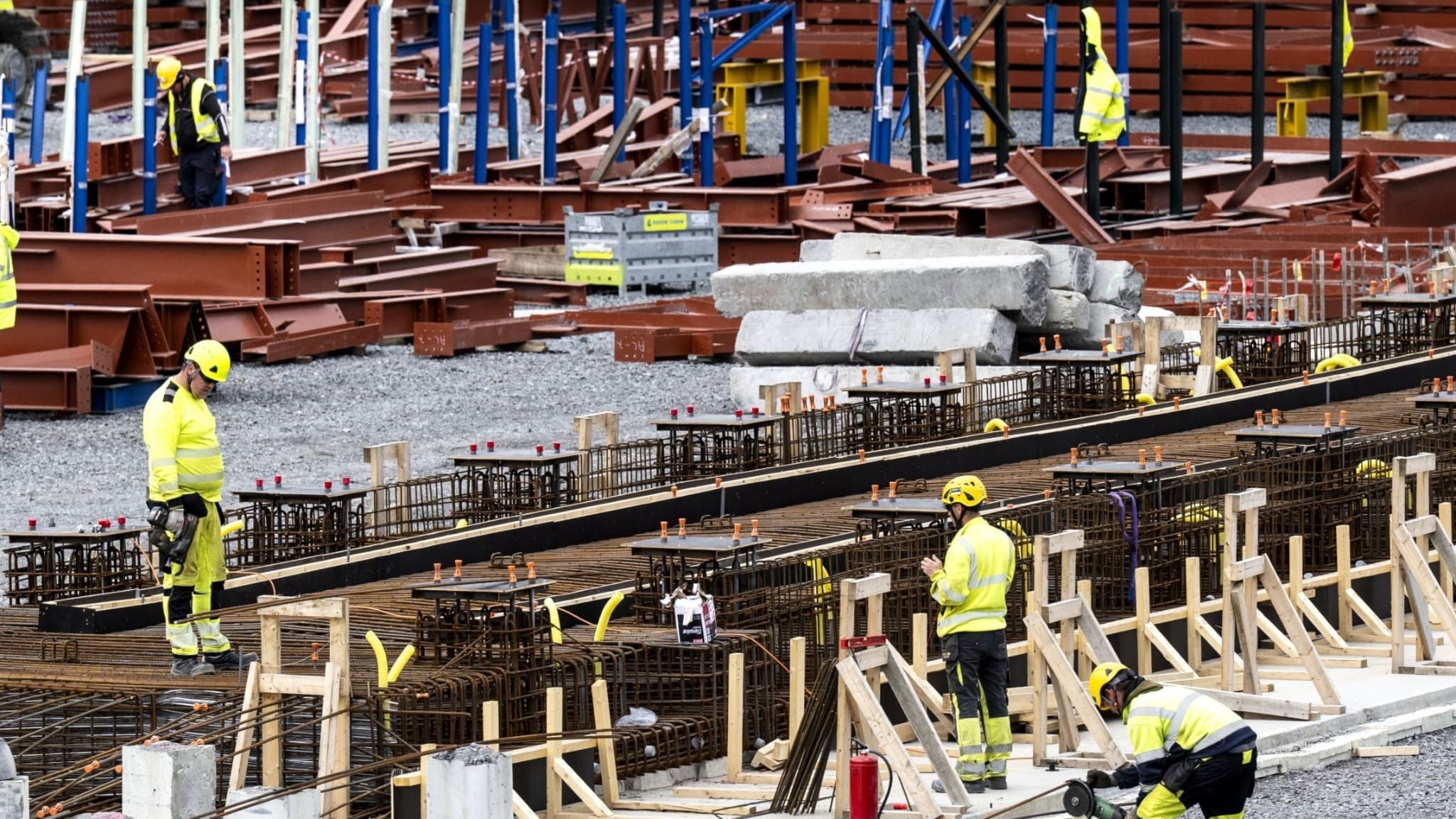 Byggarbetsplats i Boden där Stegra Green Steels nya stålverk och järnsvampstillverkningsenhet håller på att uppföras för produktion av fossilfritt stål. Byggarbetare och maskiner syns i arbete.