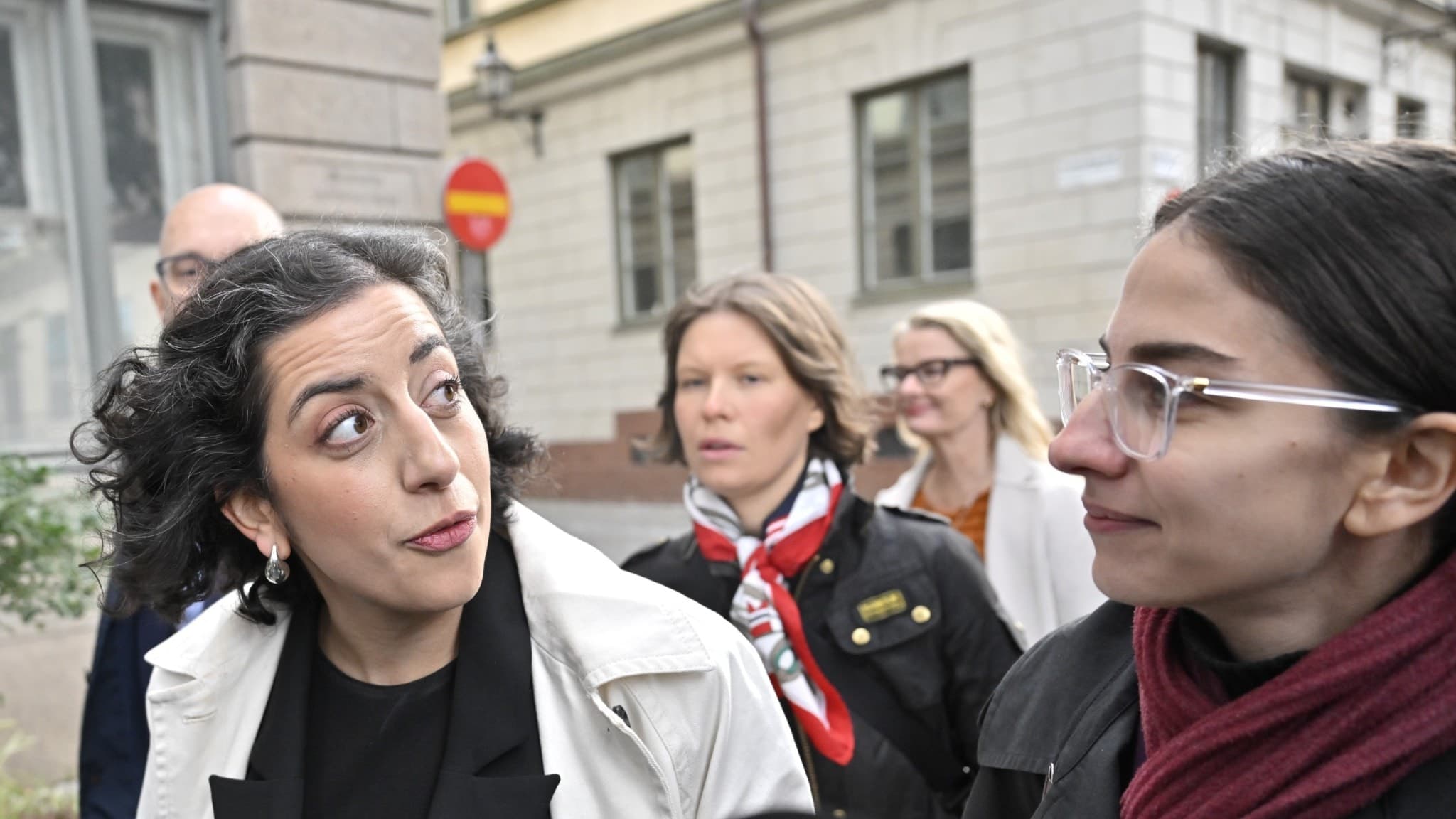 Liberalernas partiledare Simona Mohamsson ses anlända till ett partistyrelsemöte i Stockholm. Hon bär en ljus kappa och omges av mikrofoner från olika medier utomhus.