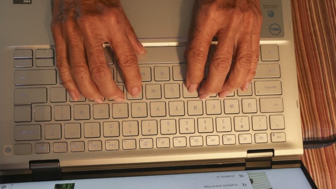 Evelina Galli, AI-techreporter, visas på vänster sida av bilden med en suddad ansiktsdetalj. Till höger syns händer som skriver på en silverfärgad laptop med en skärm som visar digitalt innehåll.