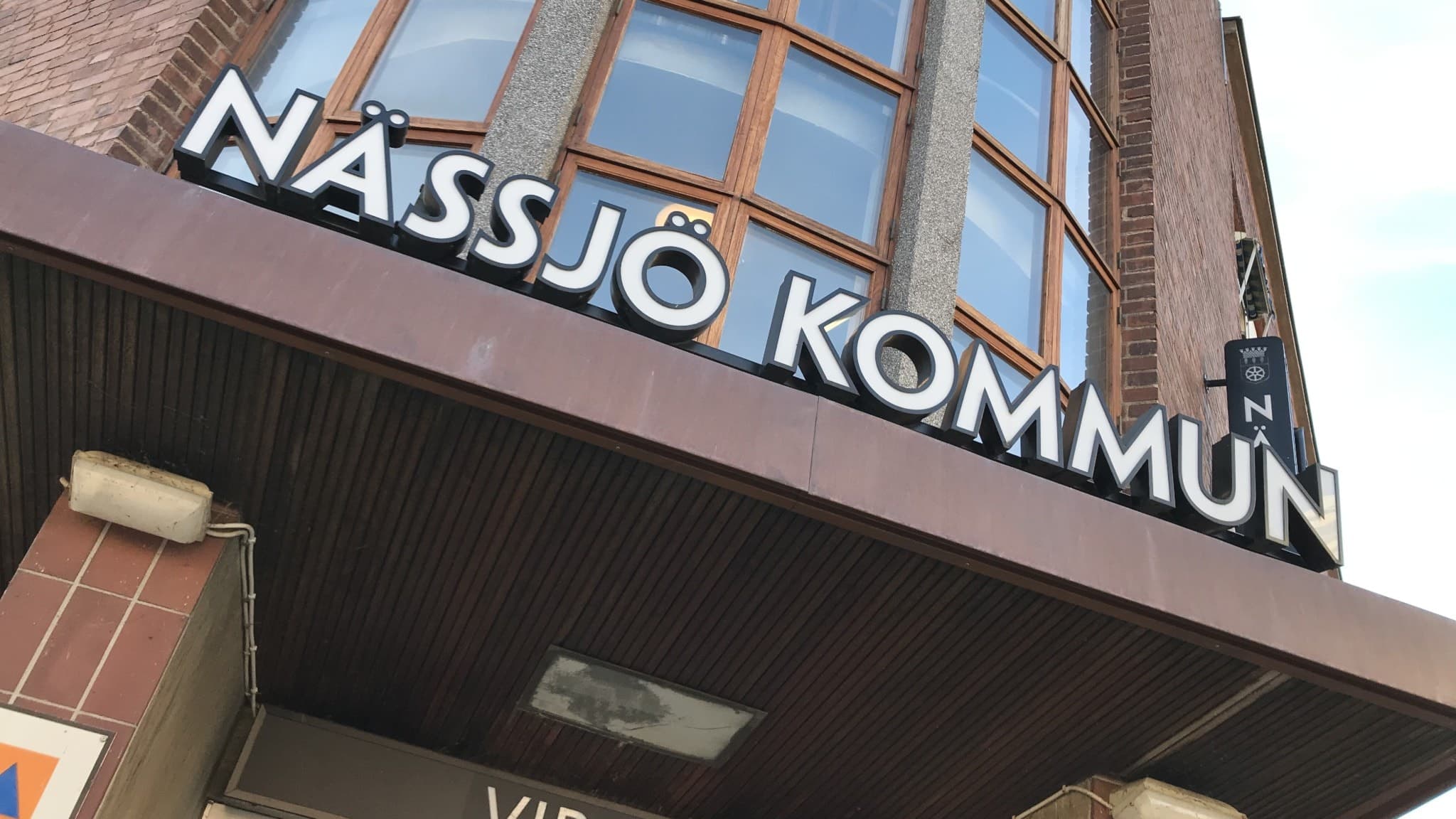 En bild på entrén till Nässjö kommuns bruna kommunhus, där det står "Nässjö kommun" med vita bokstäver ovanför ingången.