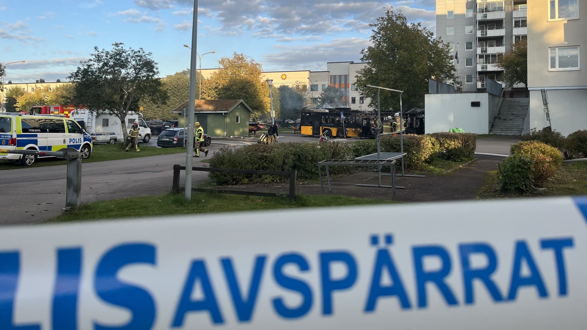 En avspärrad plats i ett bostadsområde i Karlstad efter en bussbrand i Orrholmsgaraget. Polisband syns i förgrunden och räddningstjänst arbetar vid brandplatsen.