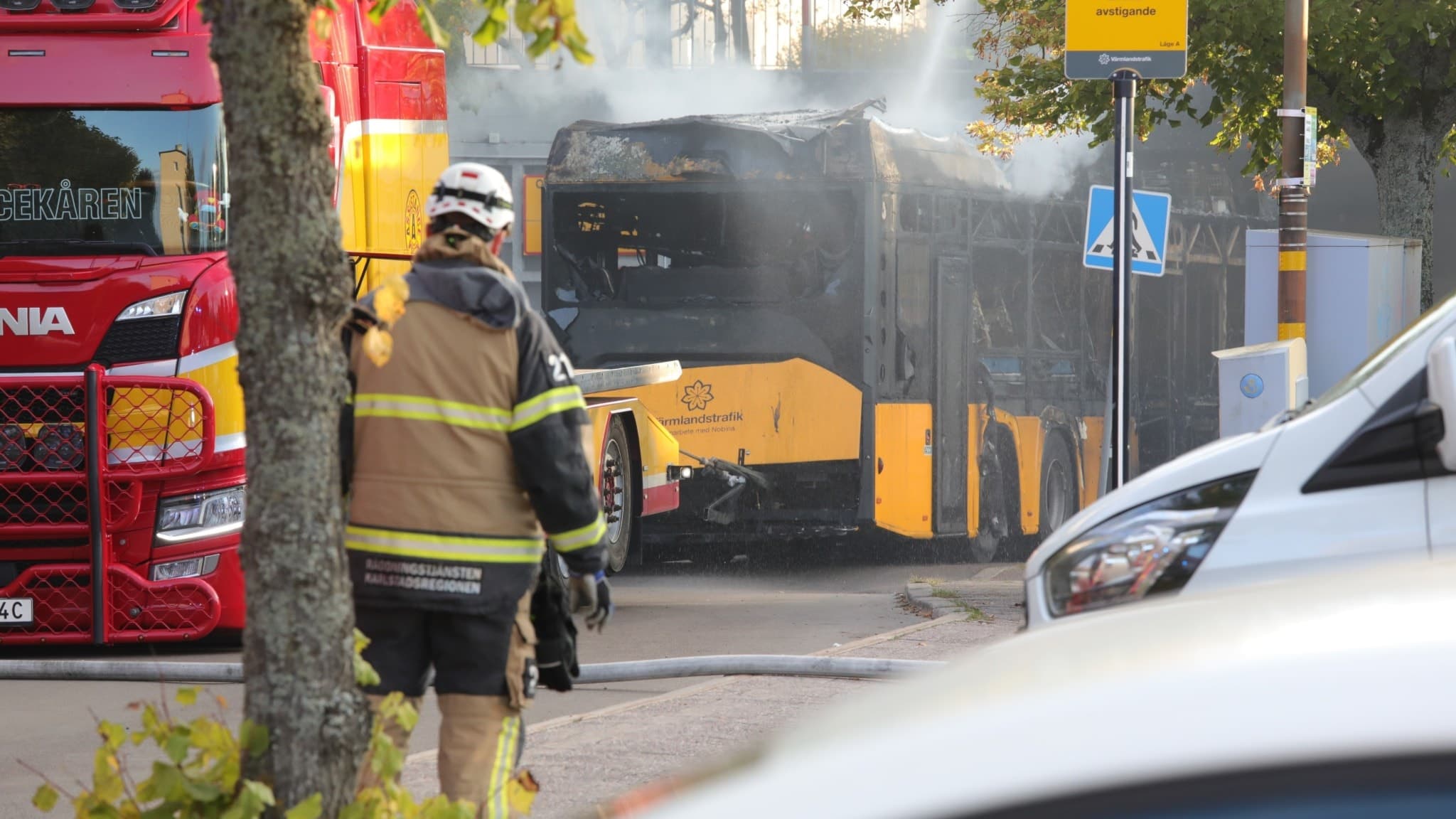 Brandman, brandbil och eldhärjad buss