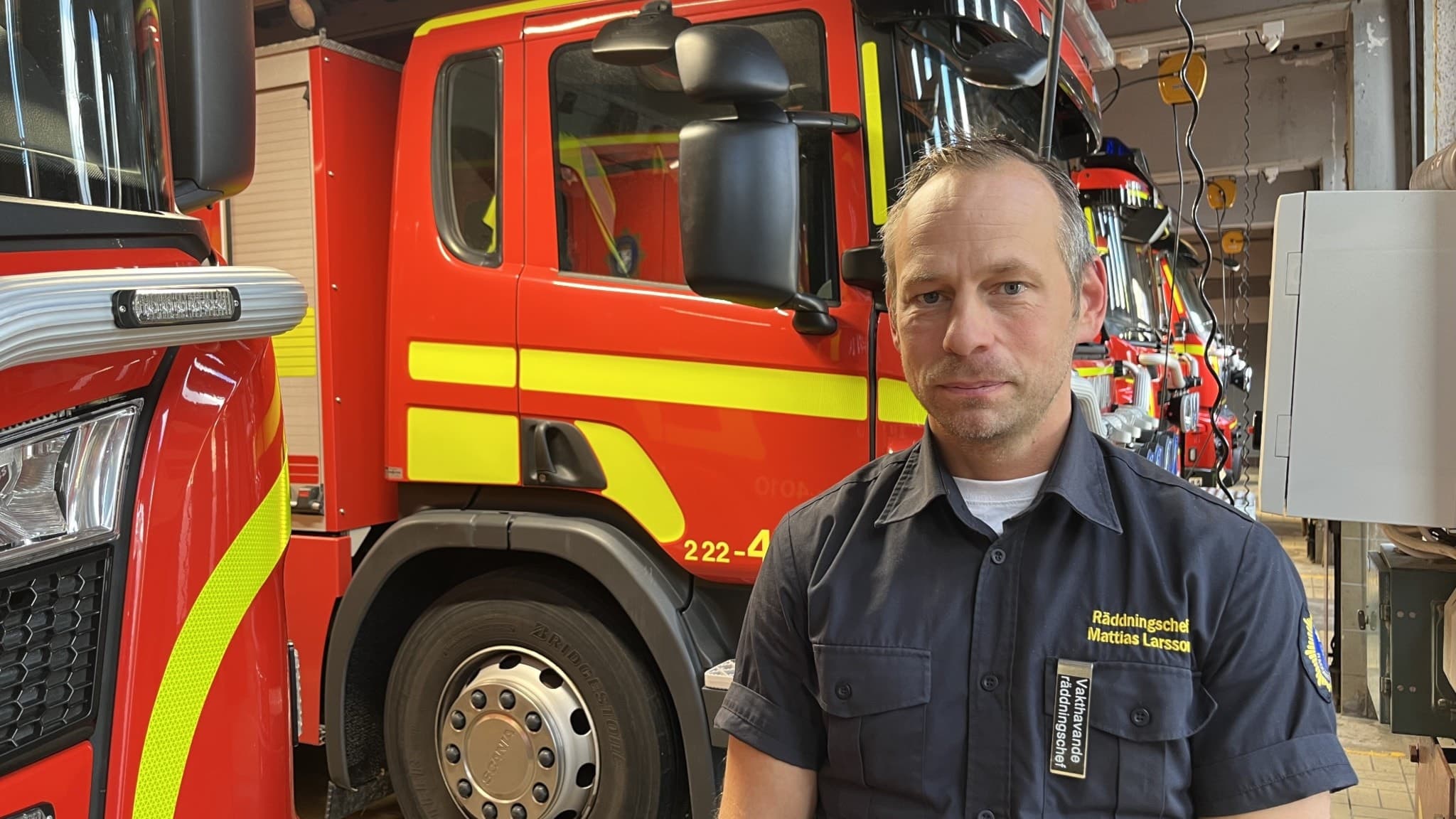 Brandman framför brandbil på brandstation.