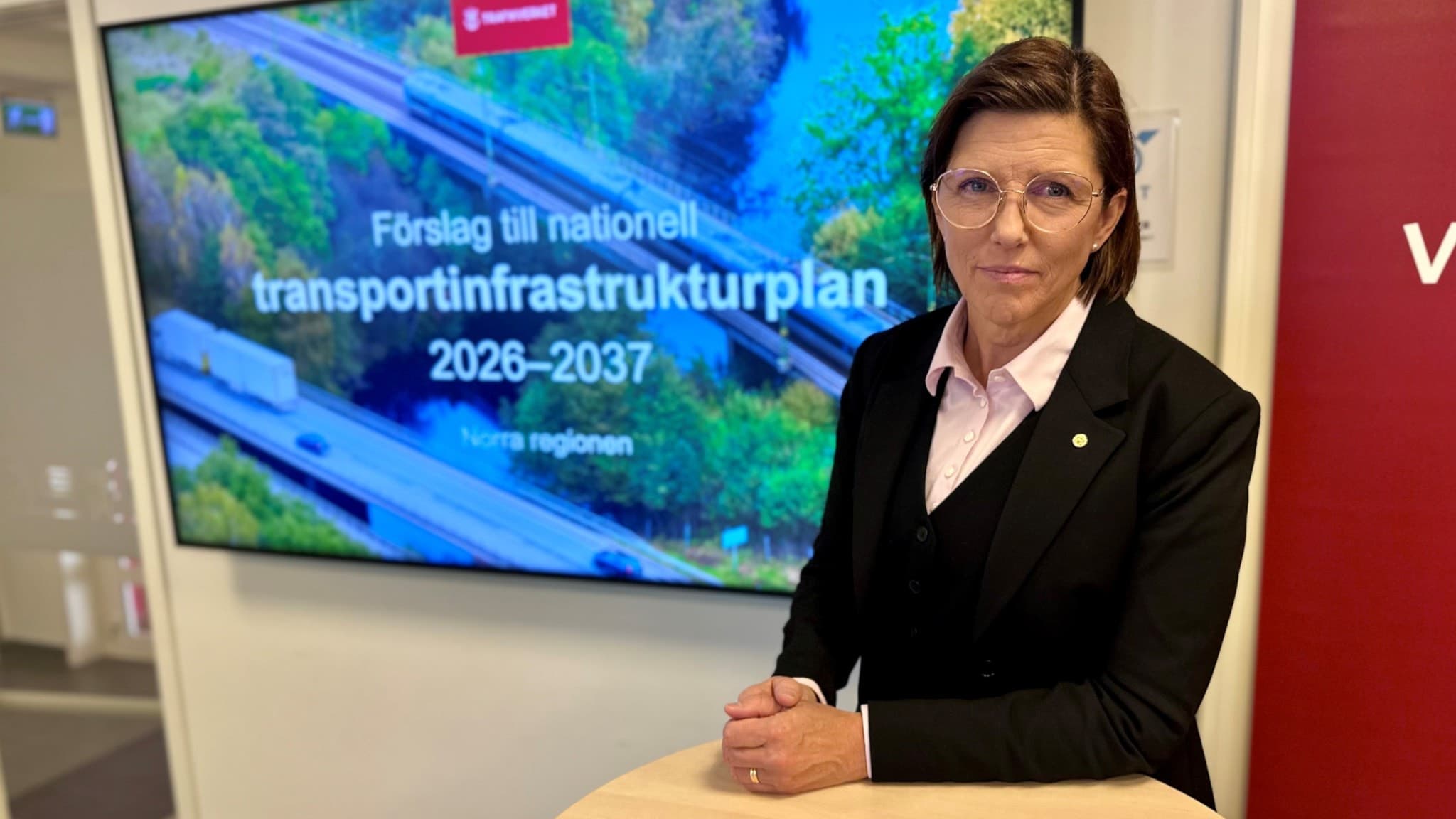 Helena Eriksson, regional direktör för Norra regionen på Trafikverket, står vid ett podium med en presentation om nationell transportinfrastrukturplan 2026–2037 på skärmen bakom sig.