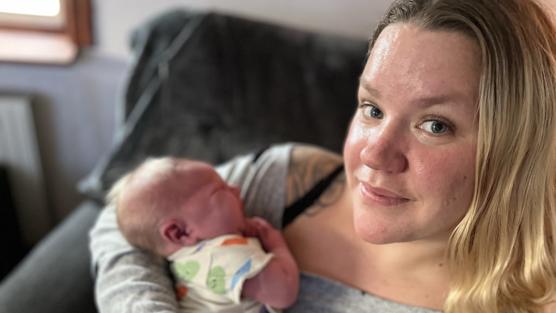 Åsa tittar in i kameran med bebisen Lo i famnen.
