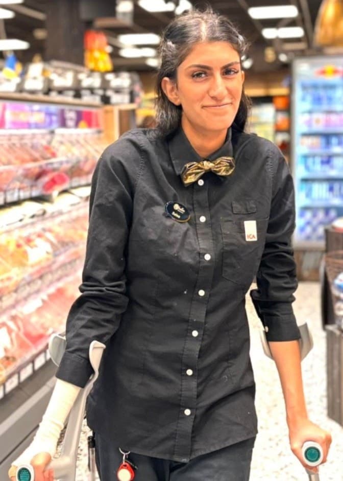 En person i svart arbetsklädsel står vid en butikshylla, och en annan person i grå pikétröja står i en kontorsmiljö. Båda befinner sig inomhus i separata miljöer. Bilden på skadad anställd blev viral – när chefen hyllade sig själv