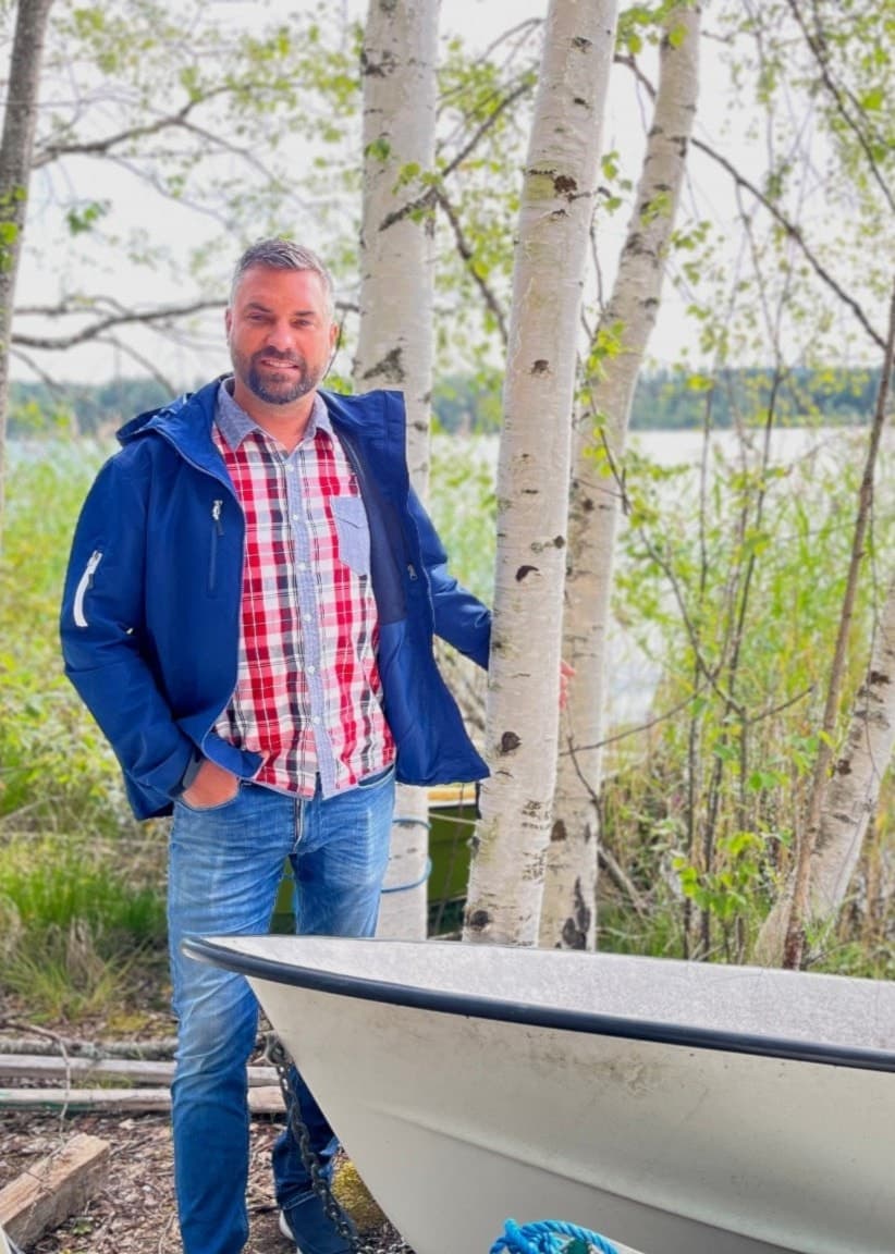 Johan Apel, ordförande för Lingheds- & Hinsen Logärdens fiskevårdsområdesförening, står vid en båt nära en sjö. Till höger syns flera falukorvar upplagda på en bricka.