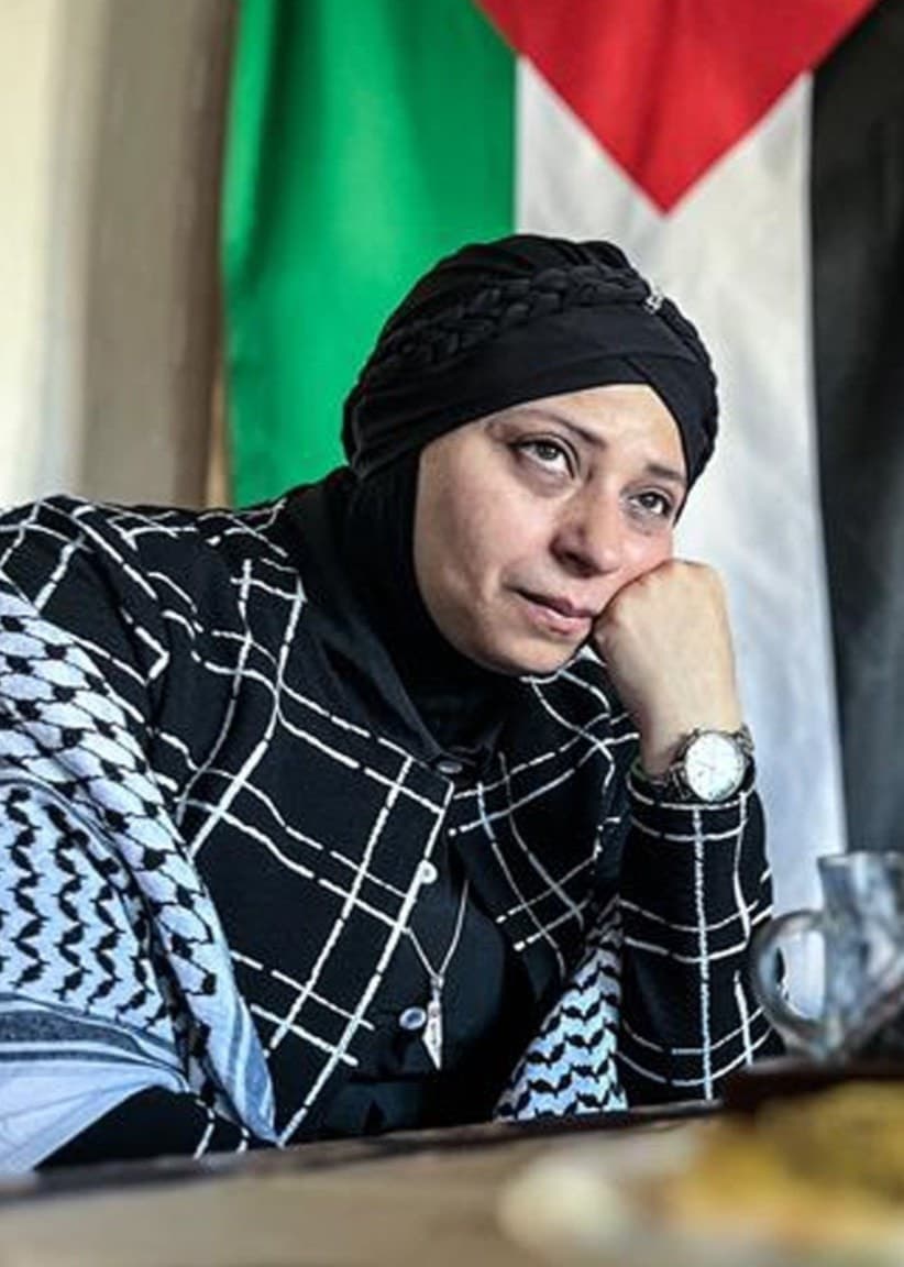 Noha Elmashouky och Helge Sonntag sitter vid ett bord med te och bröd, en palestinsk flagga syns i bakgrunden.
