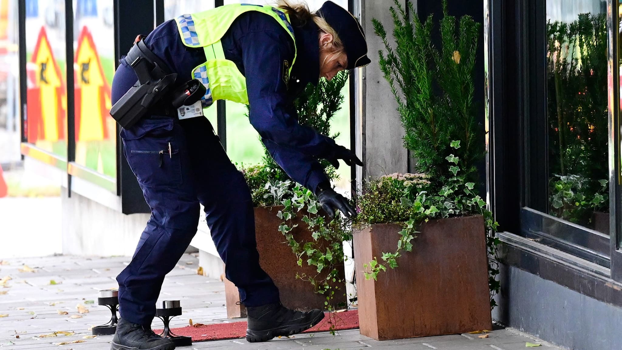 En polis inspekterar en blomlåda utanför en butik i centrala Gävle efter en skottlossning.