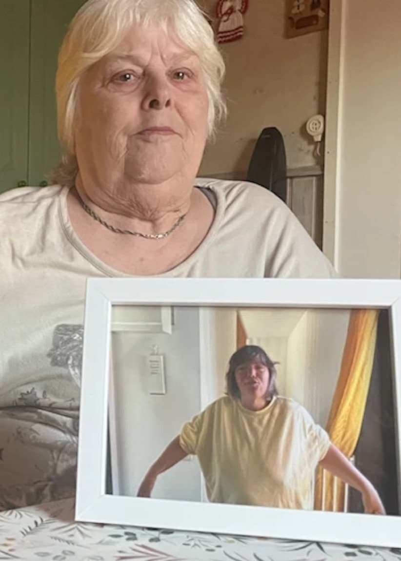 Två kvinnor visas i en delad bild. Till vänster står en kvinna utomhus vid en gata i stadsmiljö. Till höger håller en annan kvinna en inramad bild på sig själv i ett rum med gul vägg.