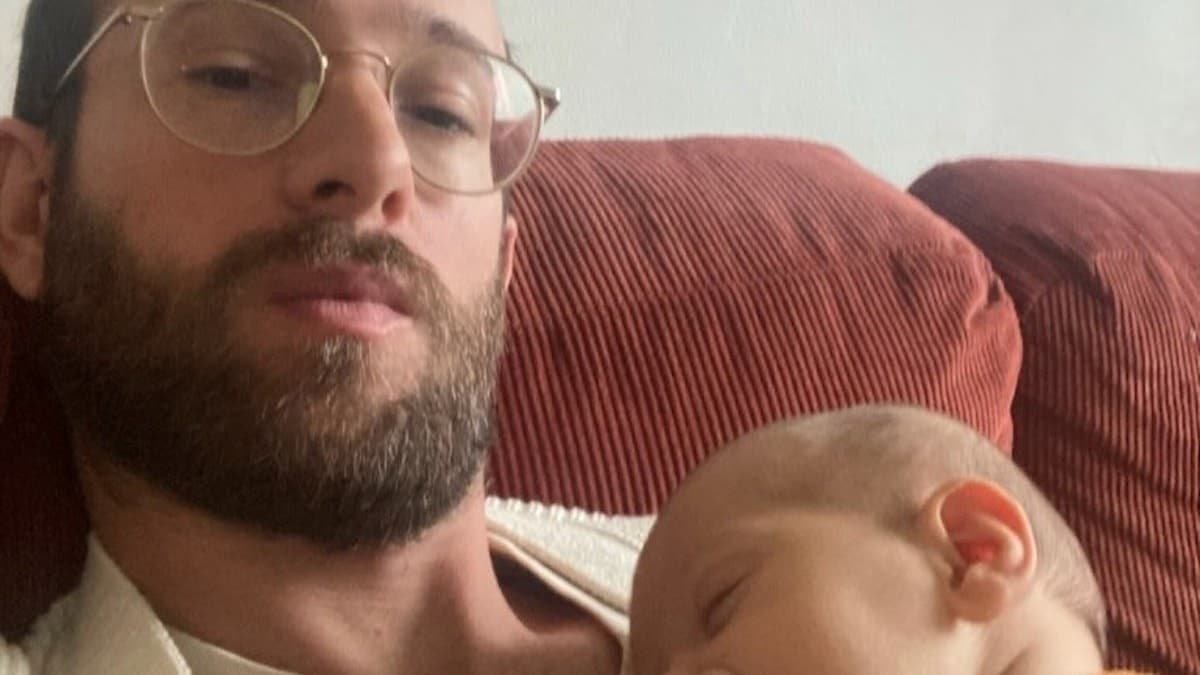 Simon med sovande bebis i famnen