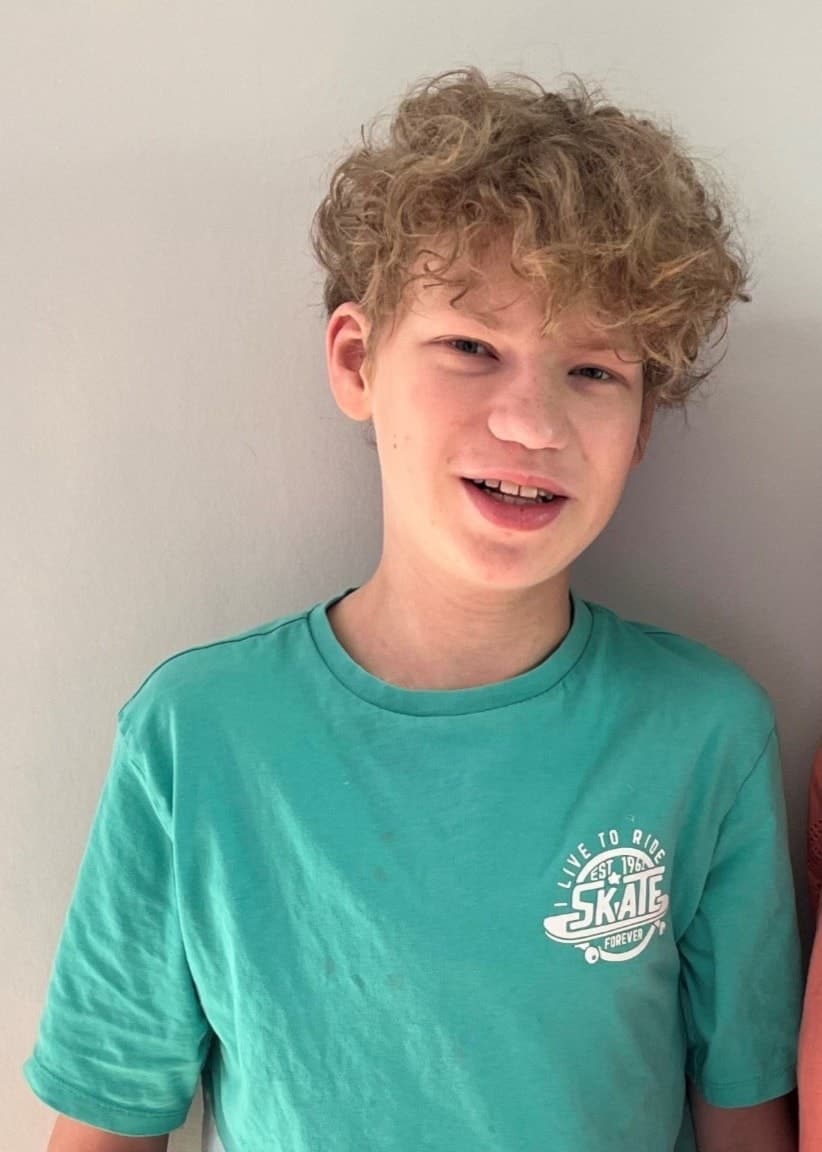 William Westermark står bredvid sin mamma Sara framför en ljus bakgrund. William har genomgått två hjärttransplantationer och är klädd i en grön tröja, medan Sara bär en korallfärgad topp.