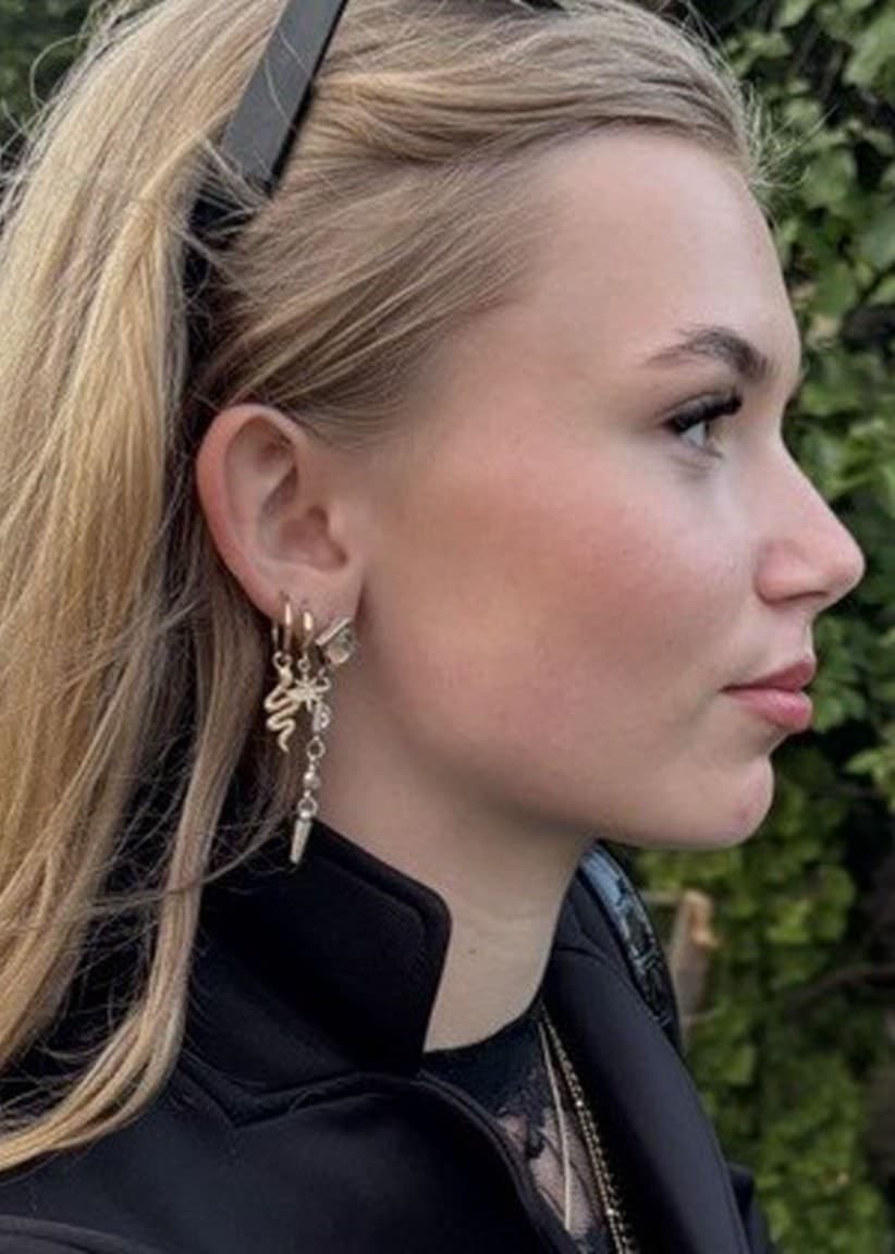 Alicia från Nybro står utomhus i en grönskande miljö, klädd i en svart jacka och med långt ljust hår.